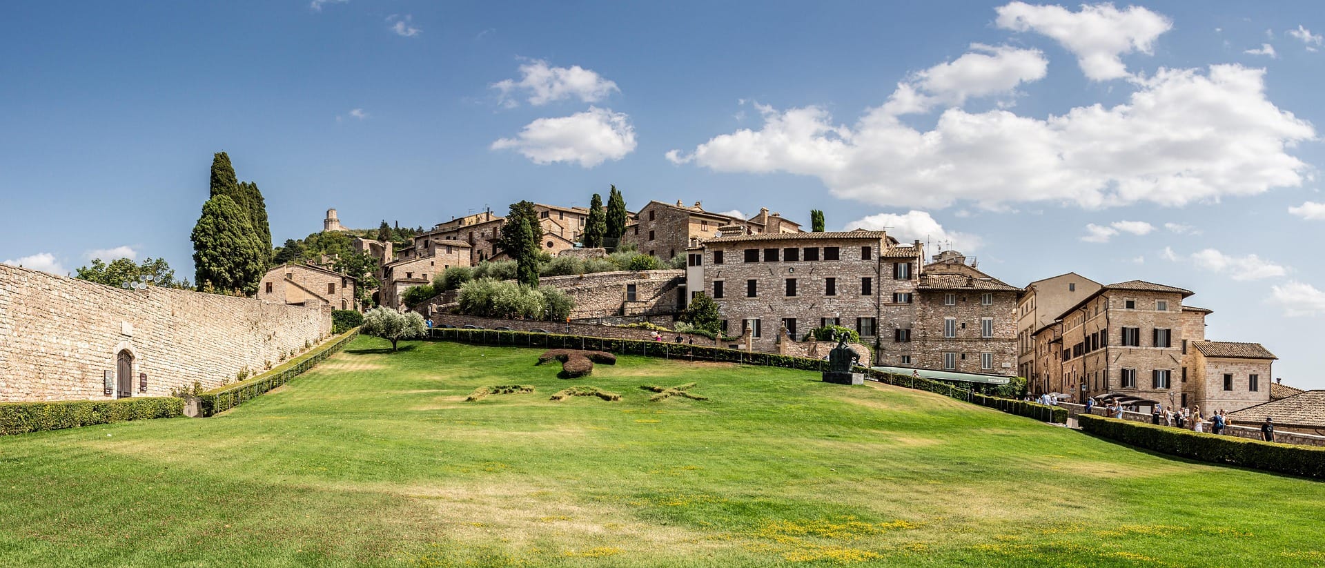 Panorama di Assisi con prati, cinta muraria medievale e centro storico, Umbria